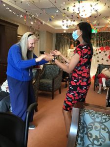 A picture containing senior woman dancing and a ceiling decorated with peace cranes. Activity for person with dementia. Senior woman with long hair.