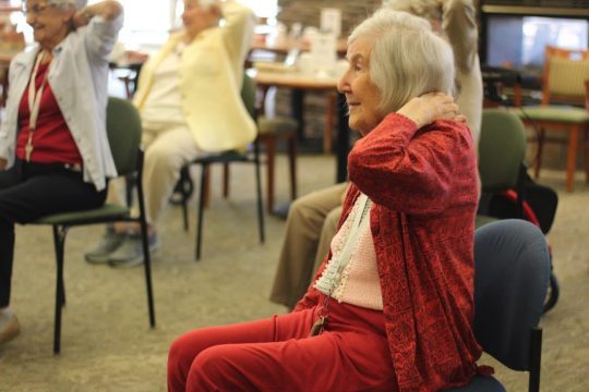 Older lady in red and pink with long hair doing exercise