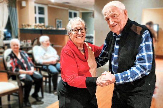 Senior couple dancing and smiling.