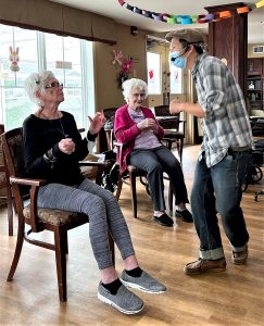 Two older women participating in a laughter yoga instructor.