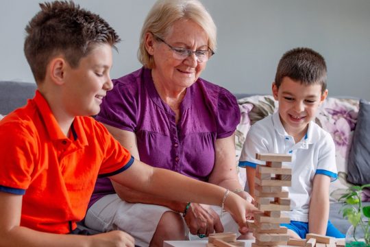 Senior woman playing Jenga with two grandsons.