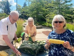 Older woman wearing sunglasses holding an ear of corn